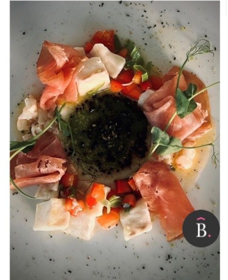 A dish from Emporia's Fine Dining menu, plated with prosciutto and fresh vegetables