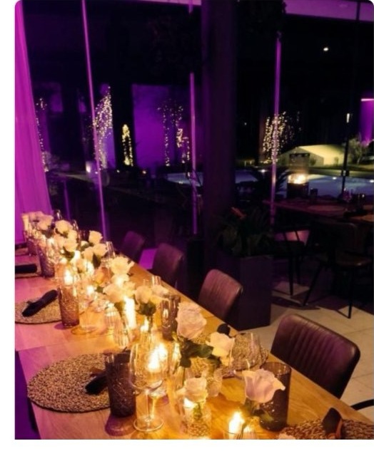 A candlelit dining table set beside Emporia's illuminated pool and vineyard, decorated for the holiday season