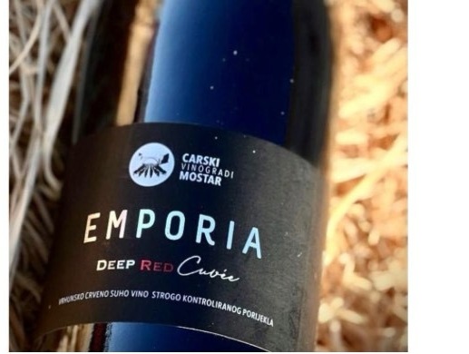 A bottle of Emporia Deep Red Cuvée from Carski Vinogradi Mostar, resting in straw