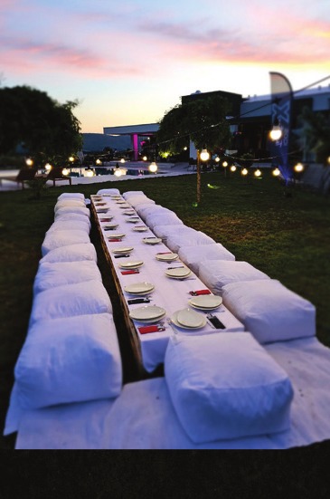 A long banquet table set for a summer evening at Emporia, lit by string lights, as submitted for National Geographic Traveller's September 2024 UK edition